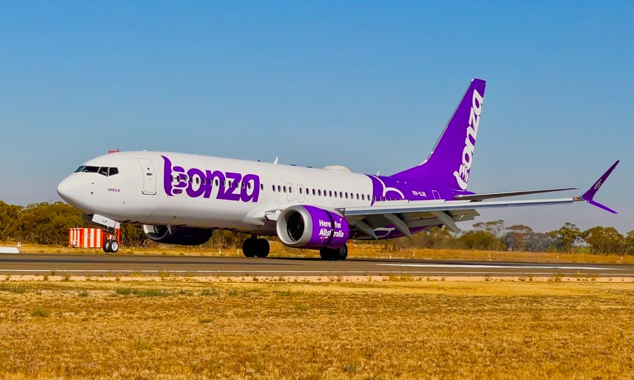 A white and purple passenger plane on a runway.