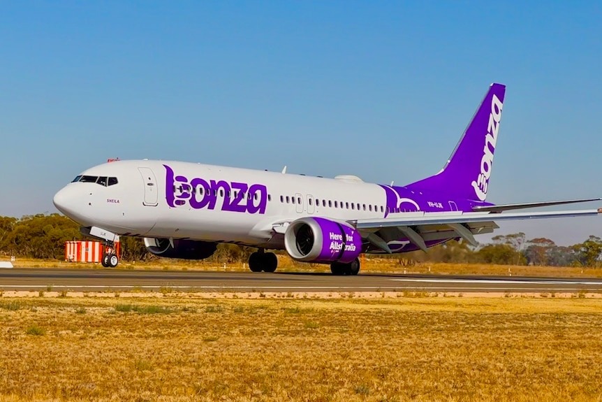 A white and purple passenger plane on a runway.