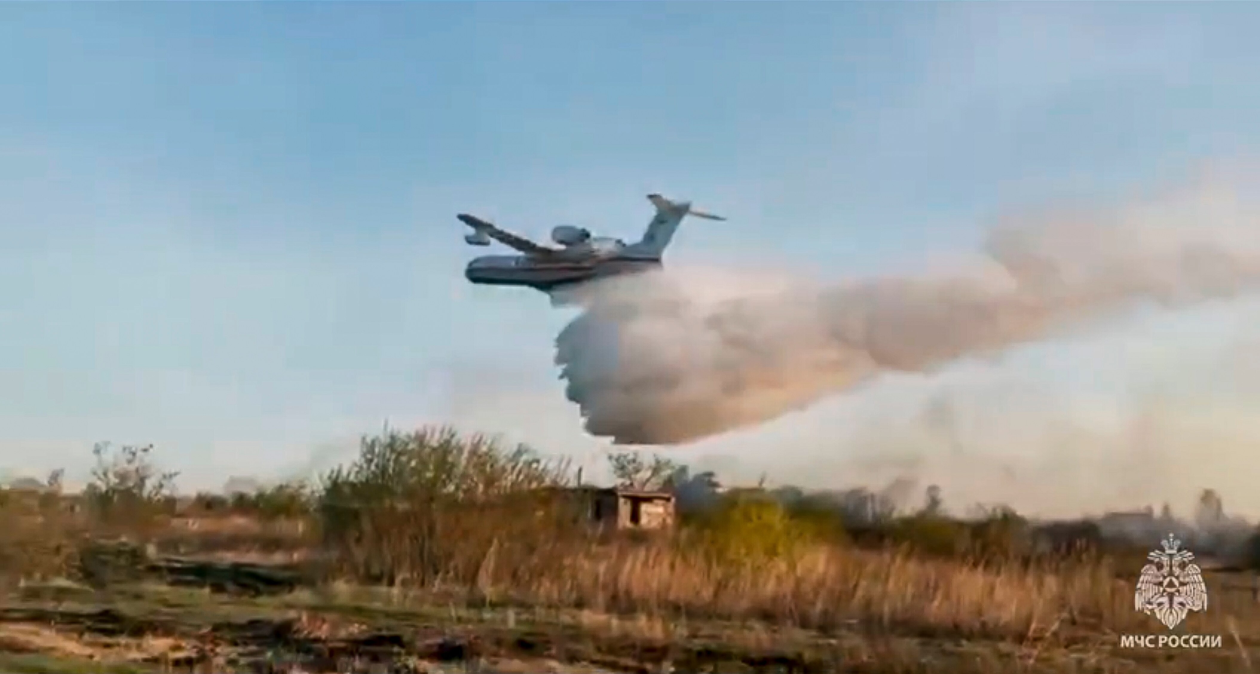 An airplane is pictured flying over a field as it is dumping water.