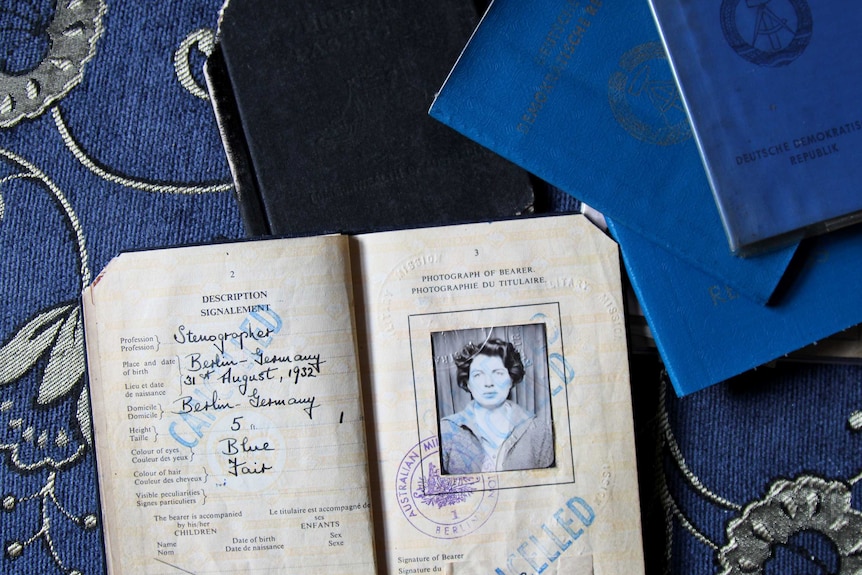 A number of old passports sit on the table including one open to an old photo of Salomea. 'Cancelled' is stamped on the pages.