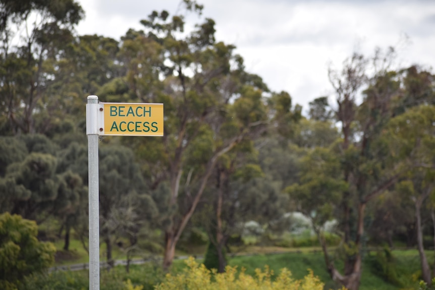 A yellow street sign reading "Beach access"