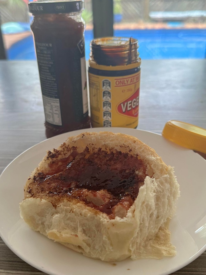 A jam and Vegemite sandwich in front of the product jars.