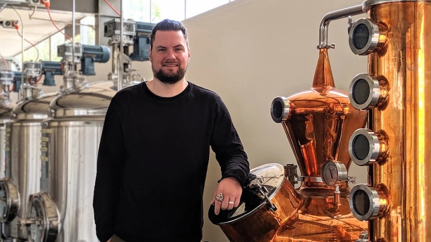 Tarrant Derksen posing for a photo in a rum distillery.