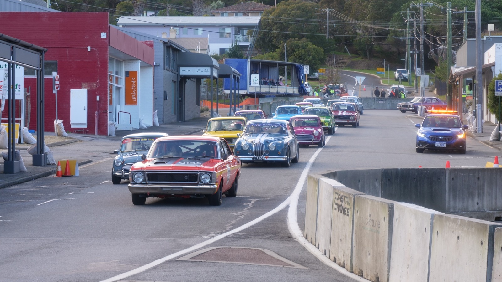 Photo of classic cars driving down the road