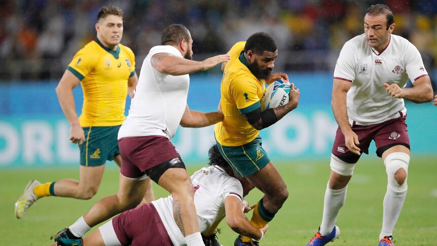 A Wallabies player holds the ball as he is tackled by Georgia players at the Rugby World Cup.