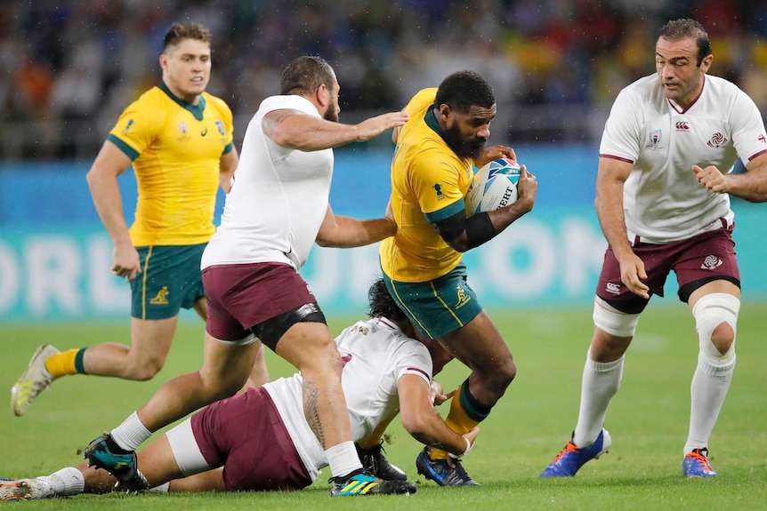 A Wallabies player holds the ball as he is tackled by Georgia players at the Rugby World Cup.