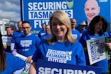 A woman stands smiling with a liberal party t-shirt on.