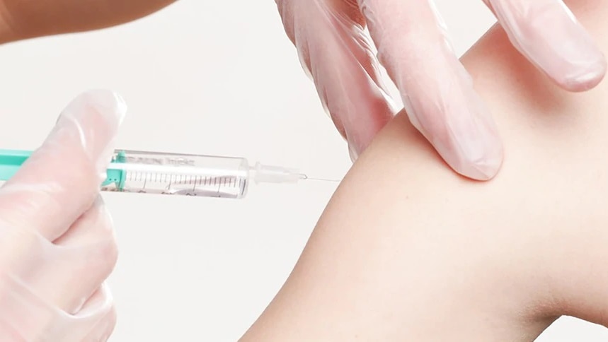 a close up of a needle about to be administered into a person receiving a covid vaccination