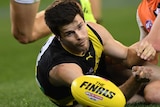 Trent Cotchin looks at the ball while laying on the ground.