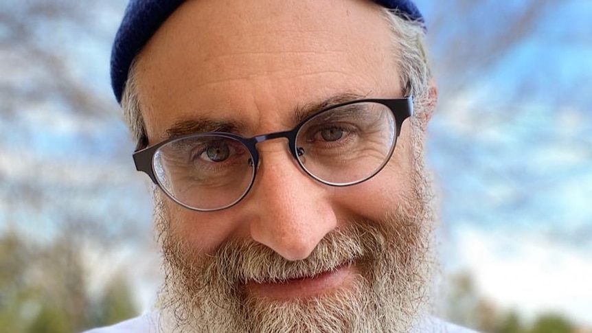 Rabbi Lee Weissman wearing blue beanie and glasses.