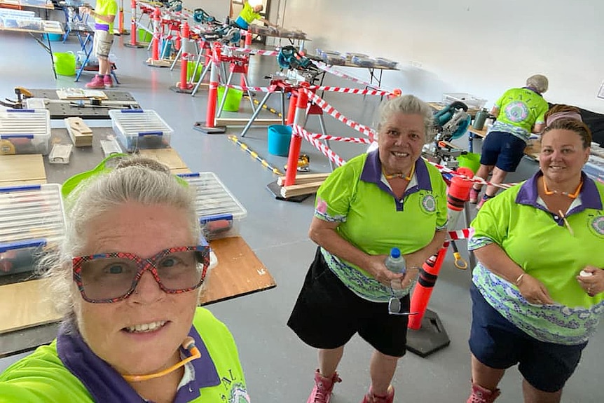 three older women stading in front of constructions materials