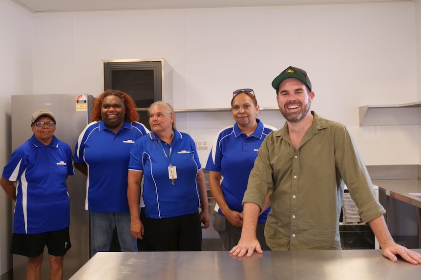 A group of people stand in front of the camera and smile.