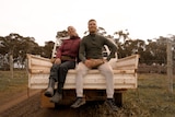 two people sitting in a ute tray