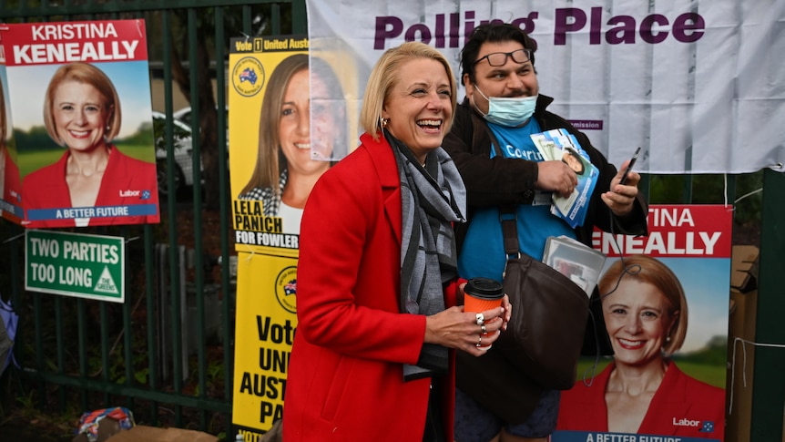 a woman smiling as she stand next to a man outside a polling booth