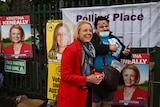 a woman smiling as she stand next to a man outside a polling booth