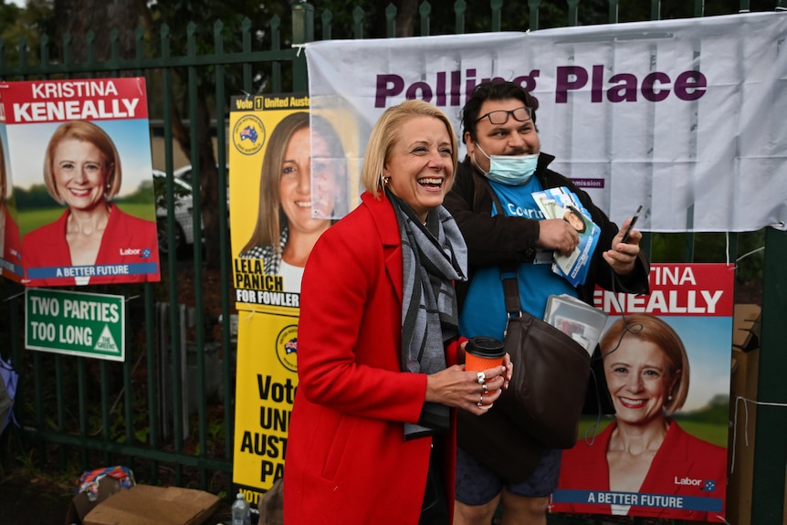 a woman smiling as she stand next to a man outside a polling booth