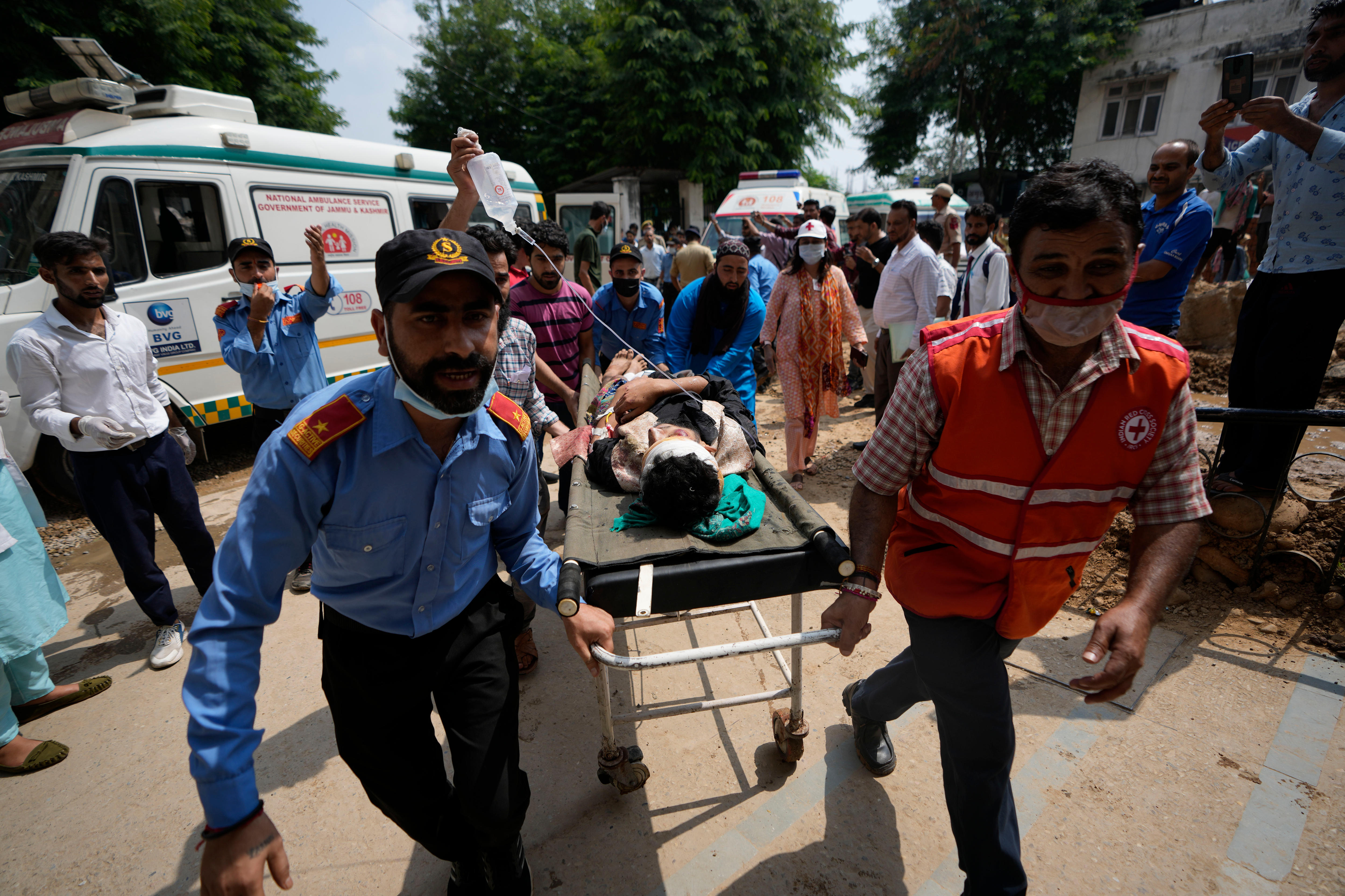 An injured man is wheeled on a stretcher by two men.