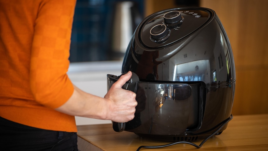 A woman operates an air fryer.