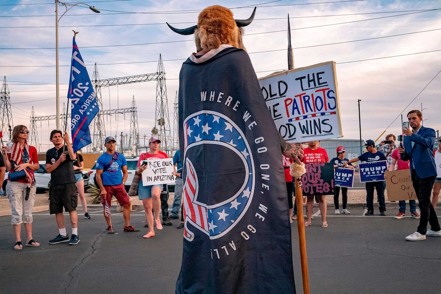 A man wrapped in a QAnon flag addresses supporters of US President Donald Trump
