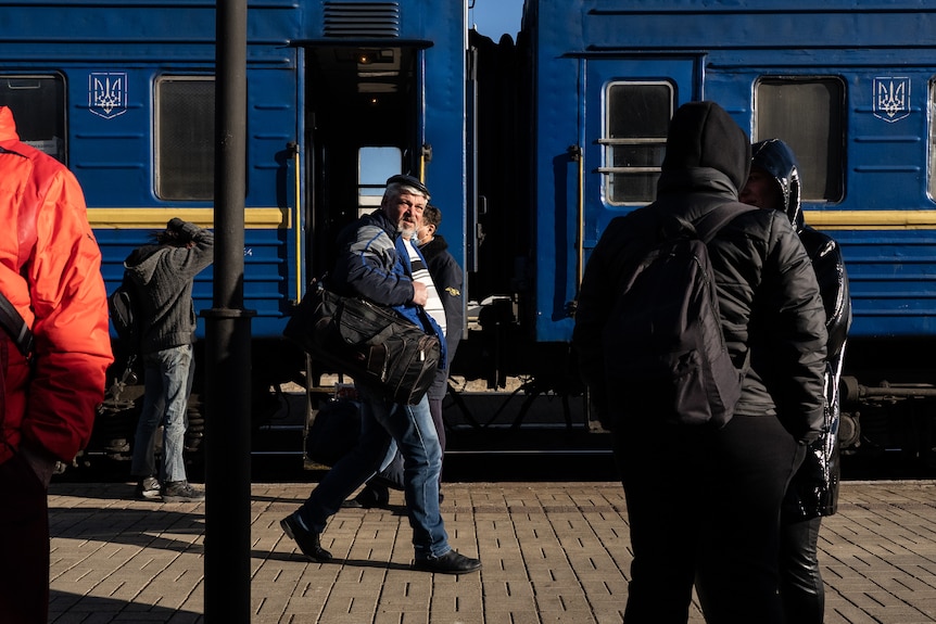 People walk down a platform at a train station.