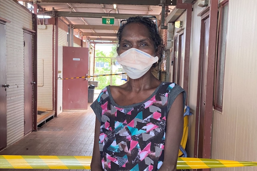 Sandra Dhamarrandji stands outside her demountable home wearing a mask.