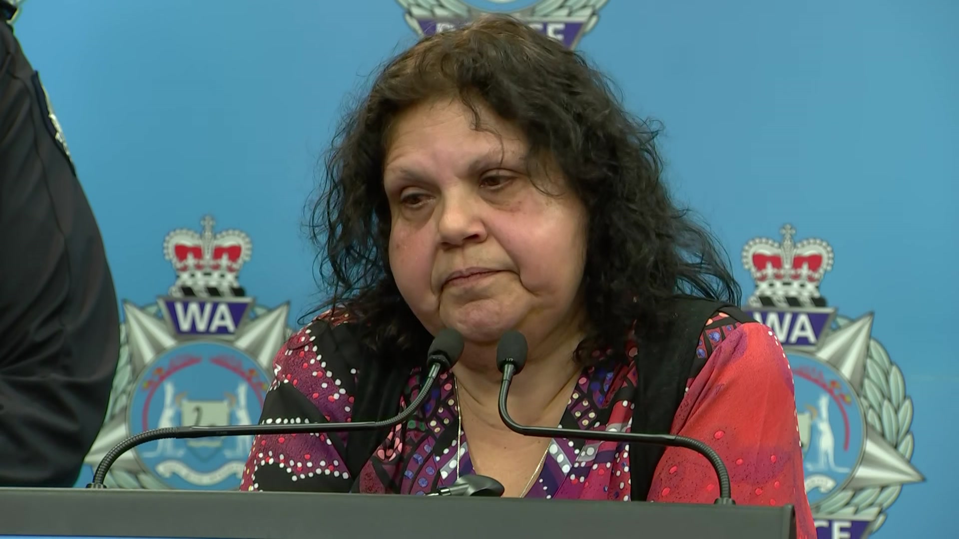 Mechelle wears a top with an Indigenous pattern as she speaks at an official police press conference