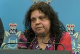 Mechelle wears a top with an Indigenous pattern as she speaks at an official police press conference