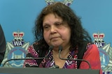 Mechelle wears a top with an Indigenous pattern as she speaks at an official police press conference