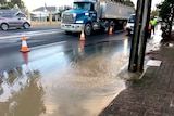 Flooding from a burst water main covers a road.