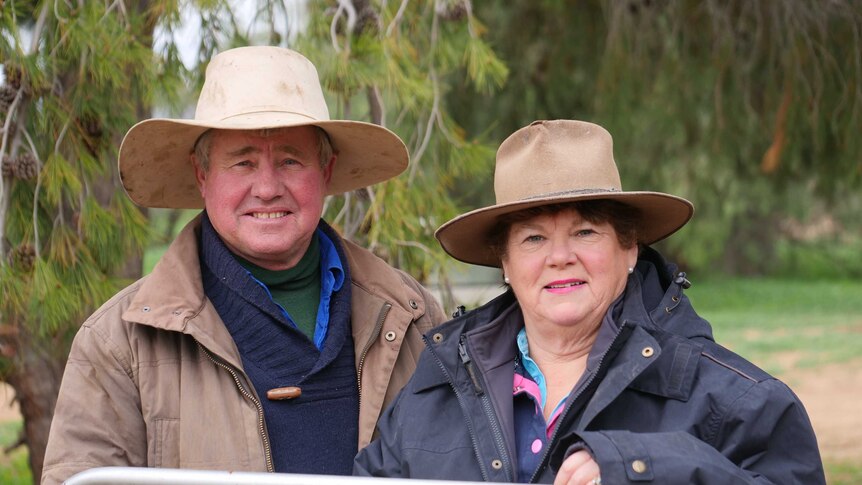 Sheep farmers Greg and Helen Rogers behind a fence at their Booligal property