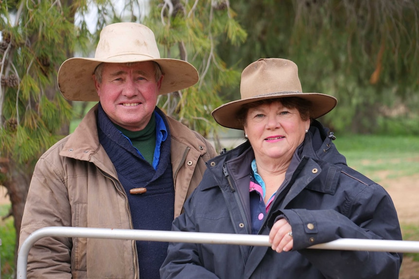 Sheep farmers Greg and Helen Rogers behind a fence at their Booligal property