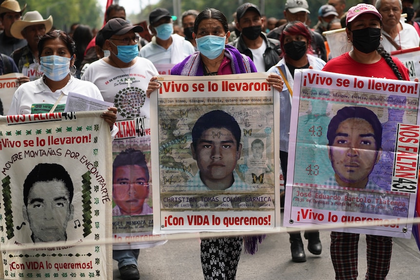 Protesters march in mexico holding photos of murdered family members