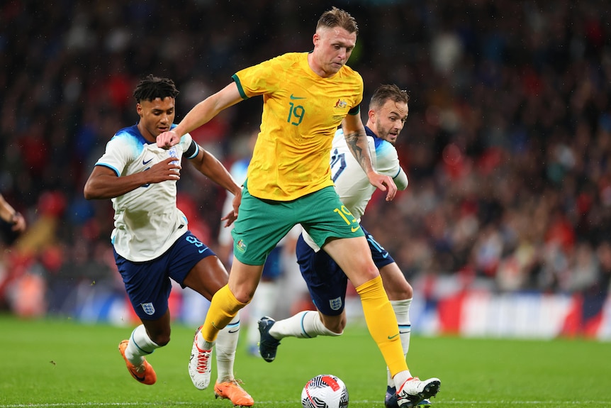 Socceroos defend Harry Souttar chases the ball as England's Ollie Watkins and James Maddison chase him.
