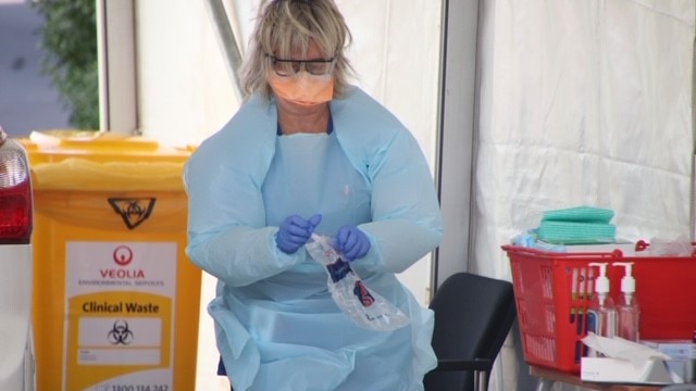 Woman wearing PPE next to a car at coronavirus testing clinic, Burnie, Tasmania, April 2020.