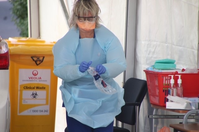 Woman wearing PPE next to a car at coronavirus testing clinic, Burnie, Tasmania, April 2020.