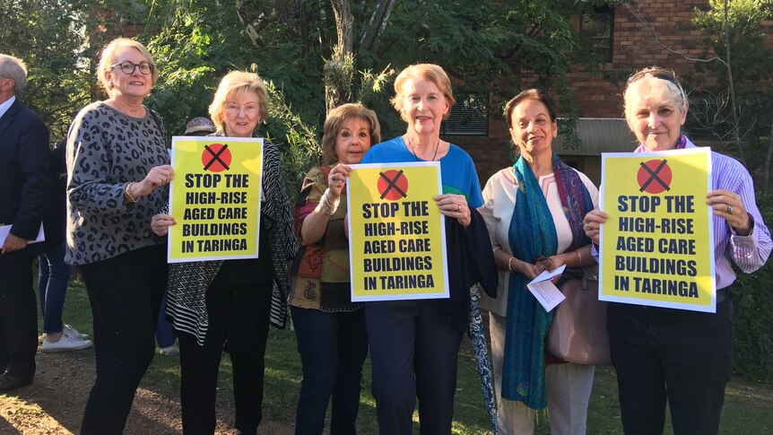 Six older women hold signs protesting a Tri-Care development in Taringa.