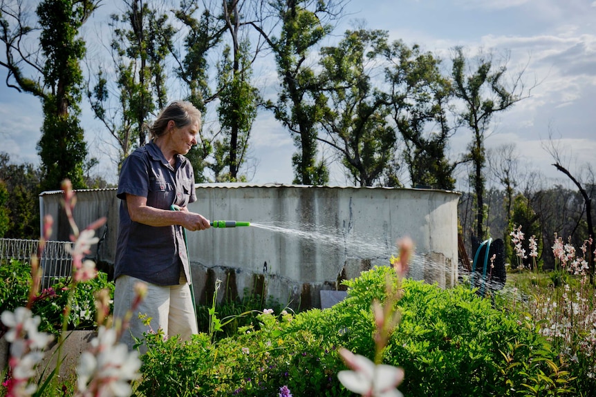 Amanda Heffernan-Buchan hoses her garden in front of a water tank.