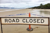 Police tape and road closed sign on beach where plane crashed.