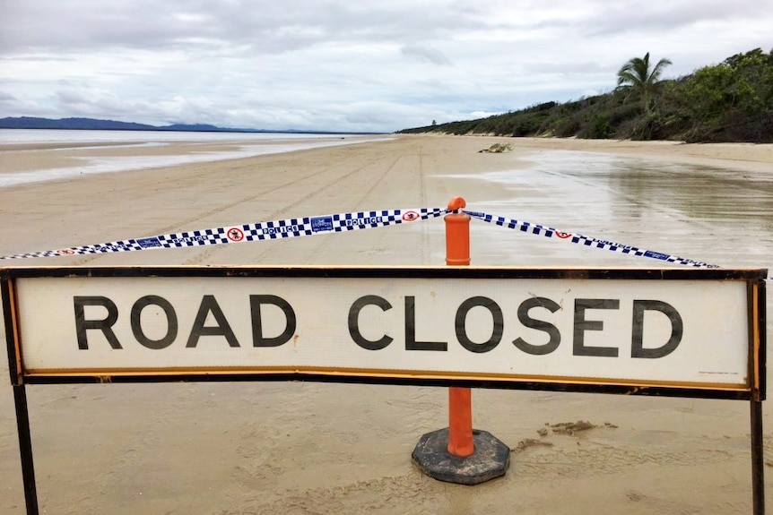 Police tape and road closed sign on beach where plane crashed.