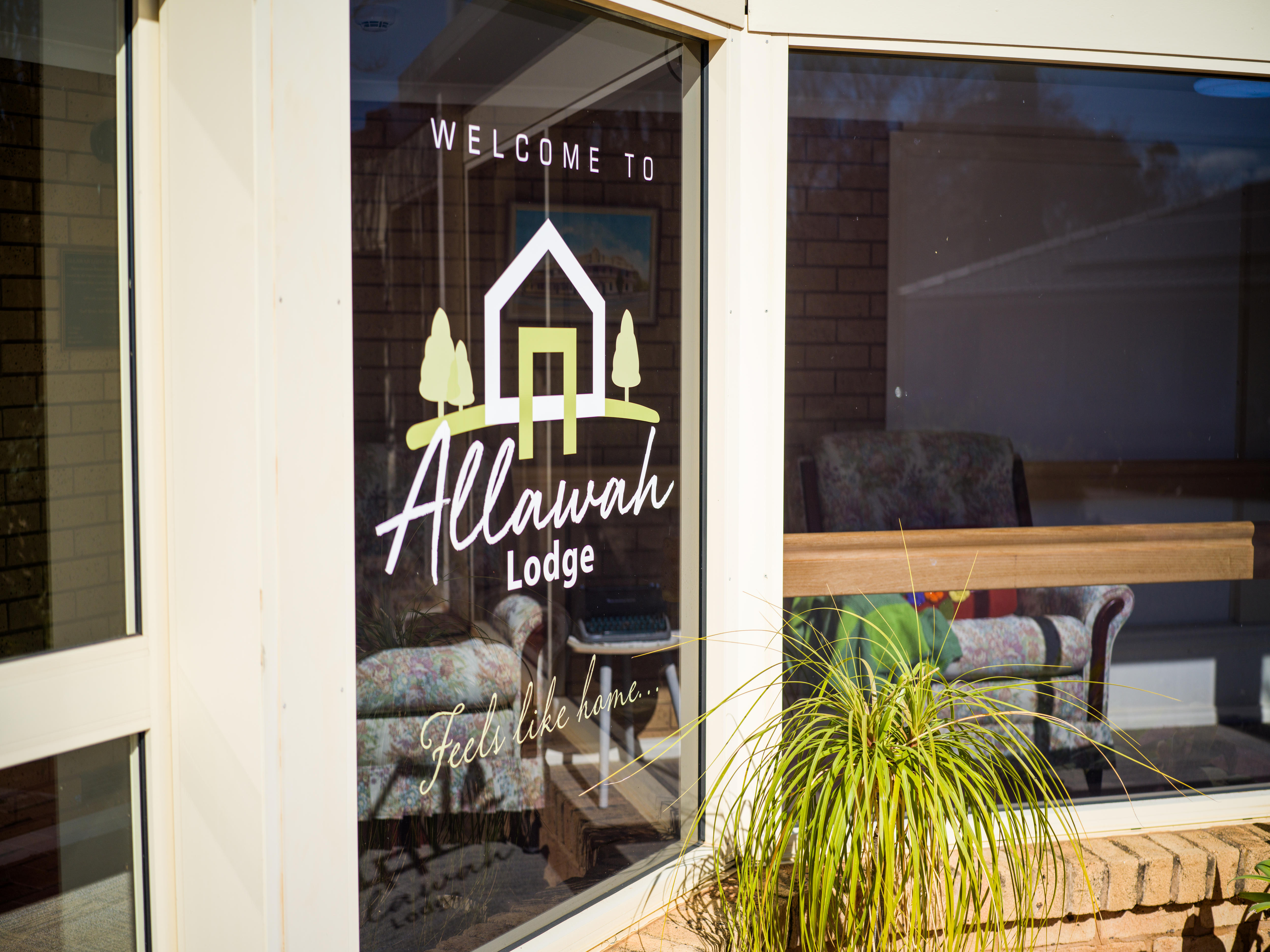 Outside residential facility, signage in window says 'Welcome to Allawah Lodge. Feels like home"