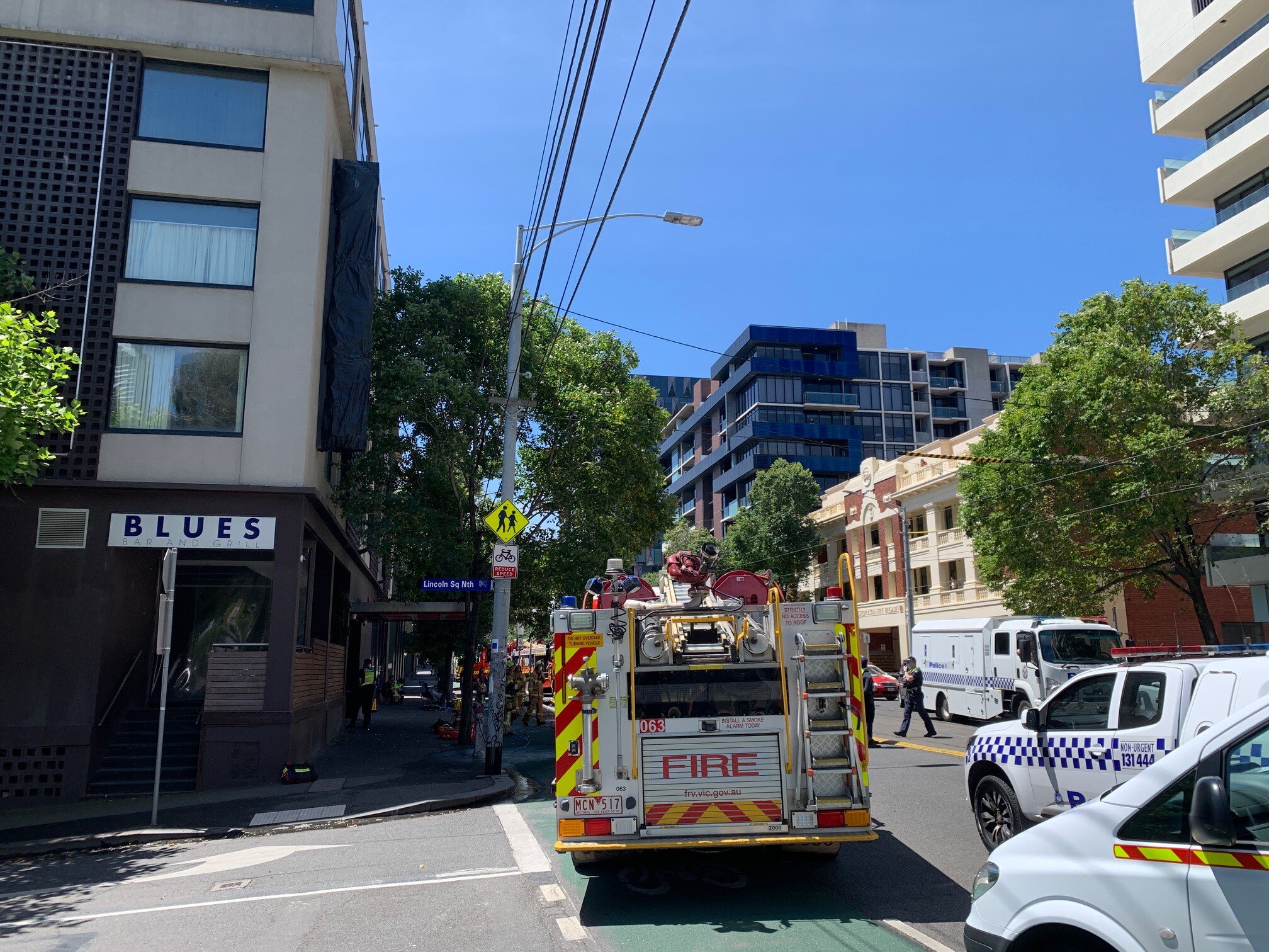 Fire truck on the corner of a street, crew in uniform seen behind.