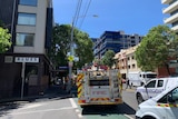 Fire truck on the corner of a street, crew in uniform seen behind.