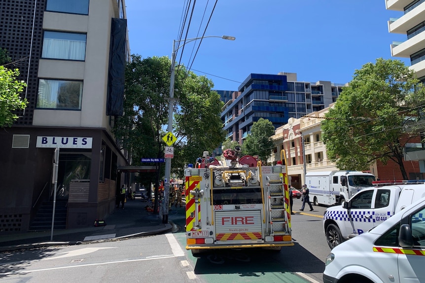 Fire truck on the corner of a street, crew in uniform seen behind.