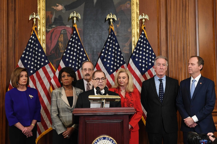 Members of the Democrat party stand in front of US flags.