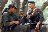FARC troop supervises a fighter as she cleans her gun