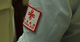 A close up of a an aid workers shirt sleeve that says China Aid in read.