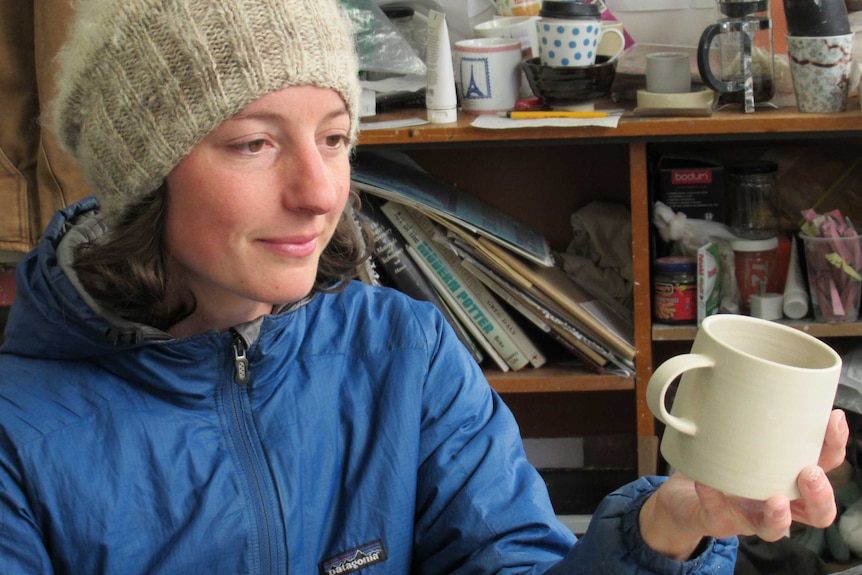 Potter Kelly Austin finishes off a cup in studio