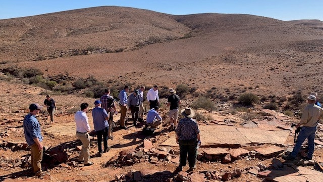 People standing on rocky land with bare hills in the background