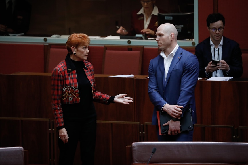 Pocock stands with hands folded as Hanson gestures while the pair speak on the senate floor.