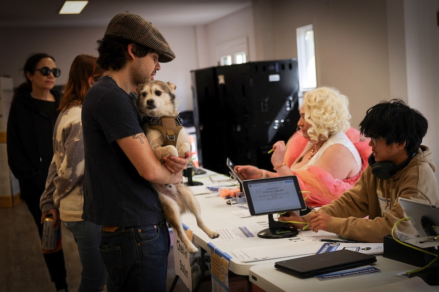 A line of voters, including a man holding a dog, sign in at a polling center during the Super Tuesday primary election.